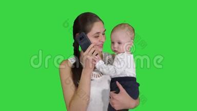 母亲，多重任务，家庭和人的概念-幸福的母亲与婴儿在绿色屏幕上呼唤智能手机